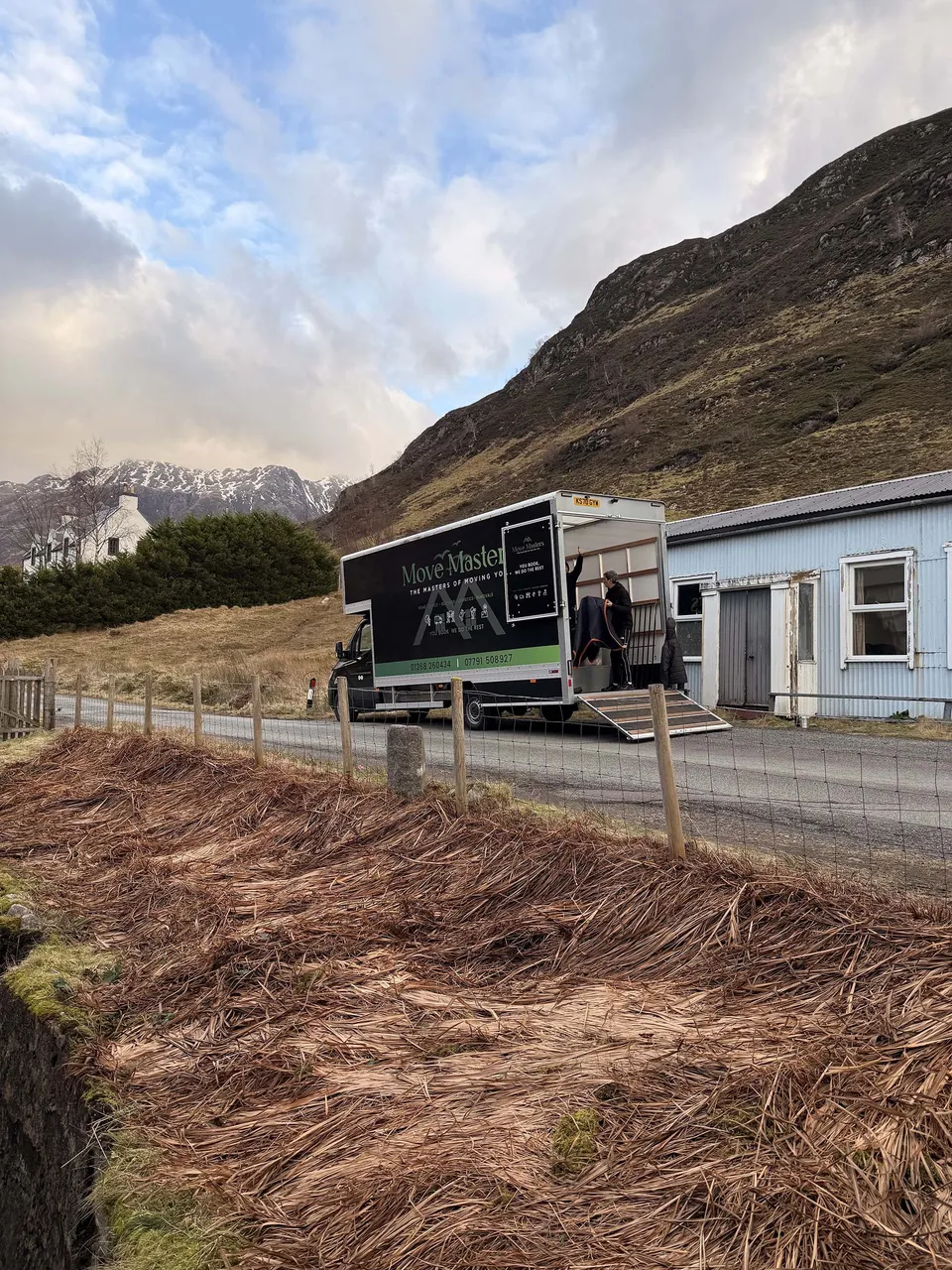 The real Move Masters removal lorry beside a building, with its loading ramp ready
